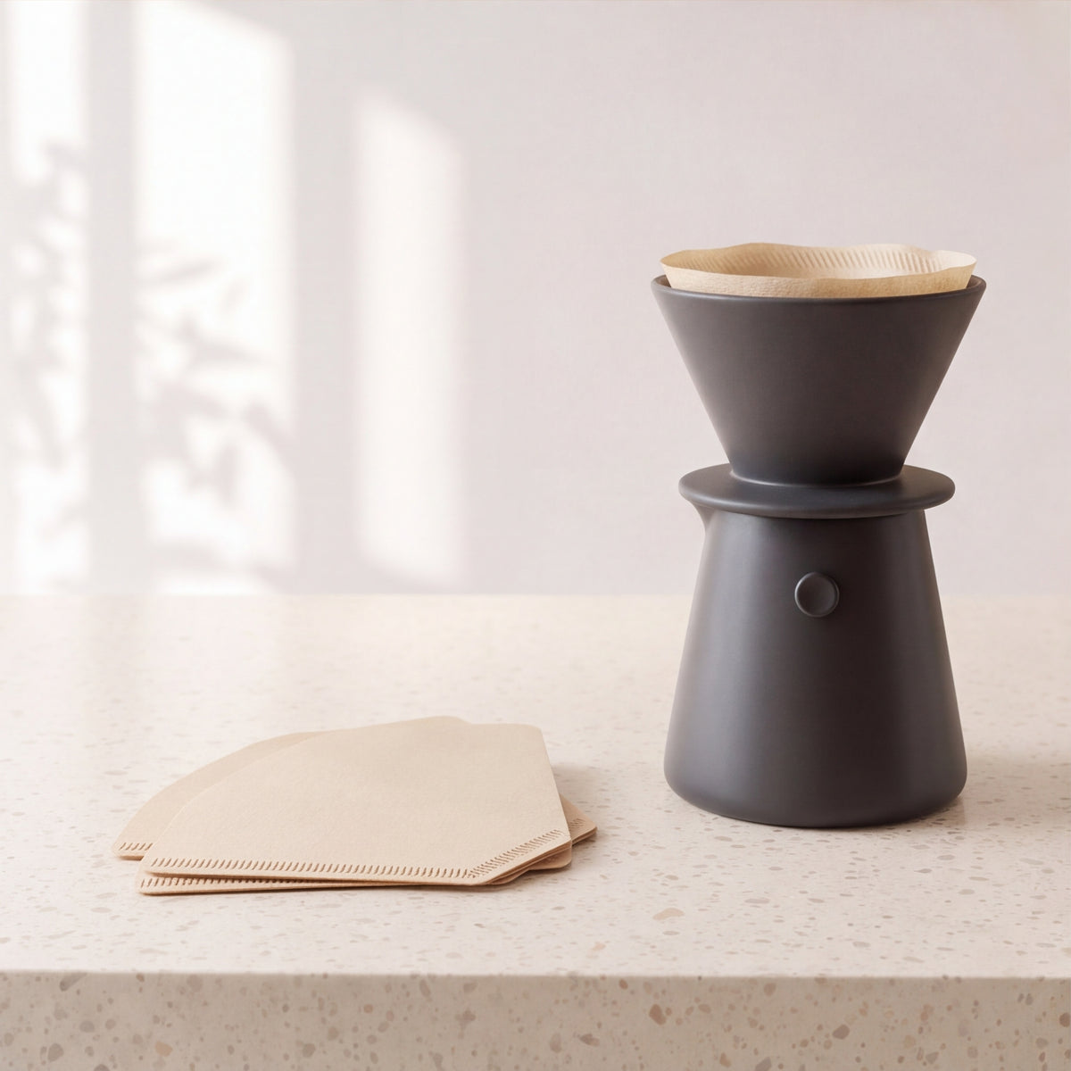 Paper cone filters next to a black pour-over dripper and carafe