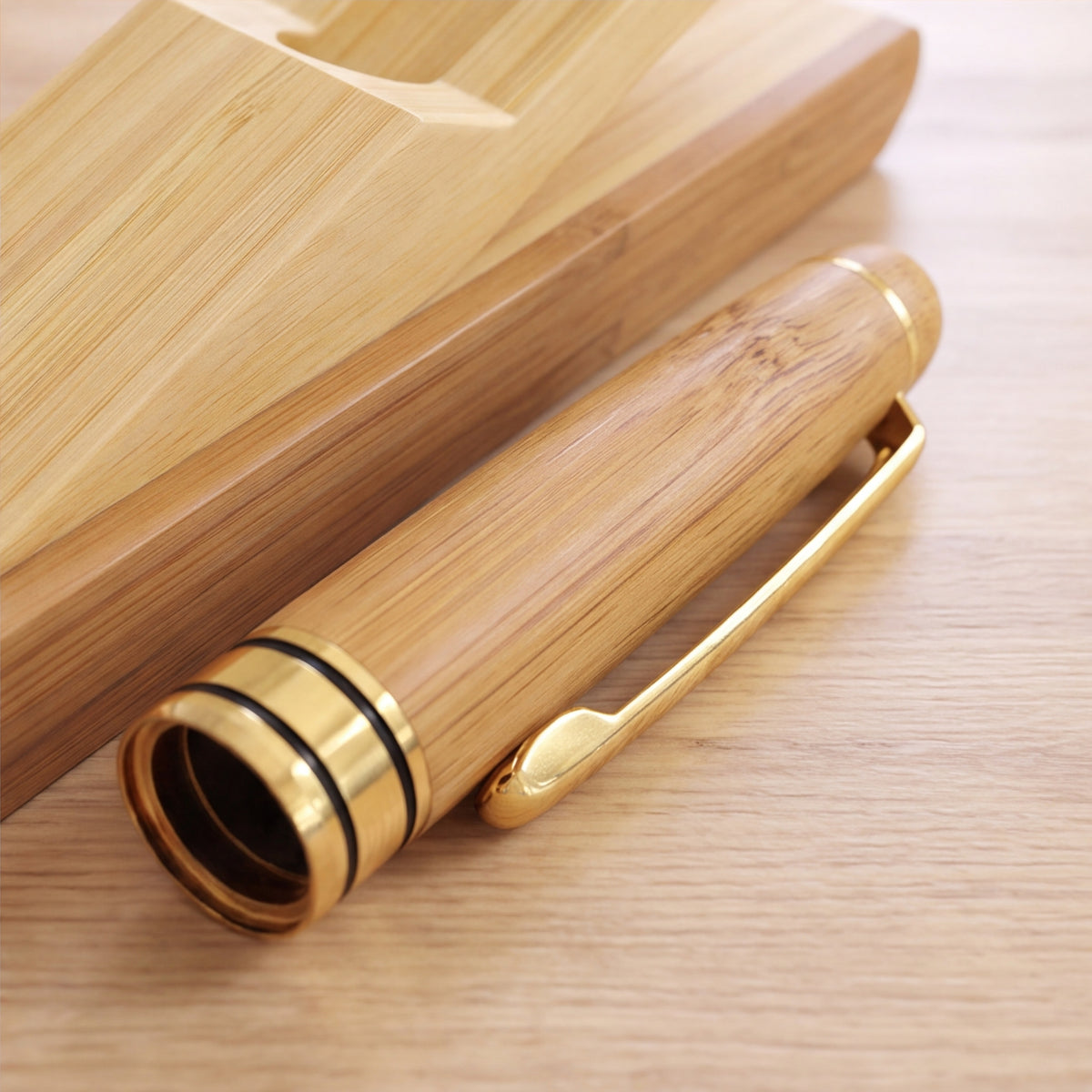 Close-up of the bamboo pen cap with gold-tone clip and trim beside the bamboo case