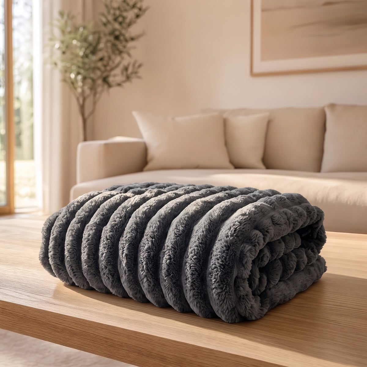The Burrow Throw in Charcoal, a dark gray ribbed faux fur blanket folded on a light wood coffee table