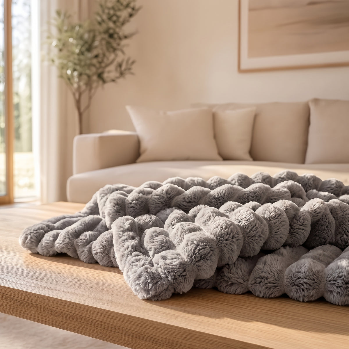 The Burrow Throw in Stone, a medium warm gray ribbed faux fur blanket folded on a wood coffee table